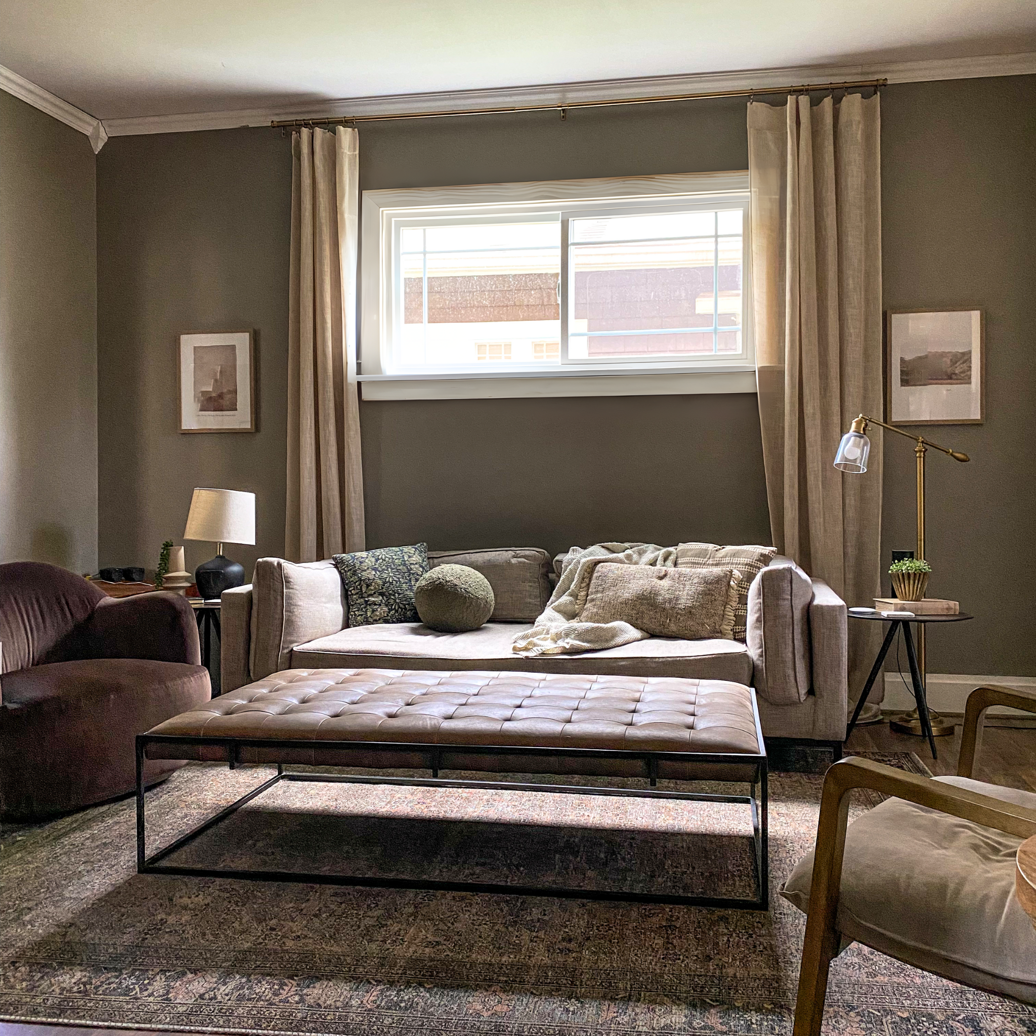 Real after image from a design client. Showcasing moody velvet swivel chairs, dark cognac leather ottoman, slingback chair, bench cushion sofa, and painted walls.